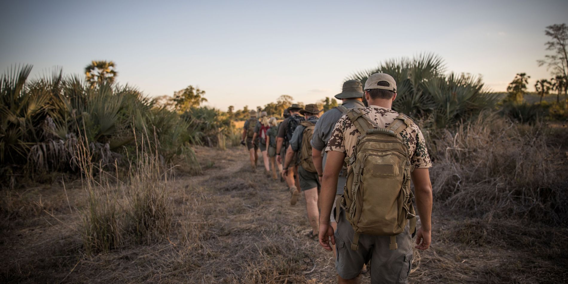 Eine Gruppe von Teilnehmern wandert bei einem Busch Walk durch die afrikanische Landschaft