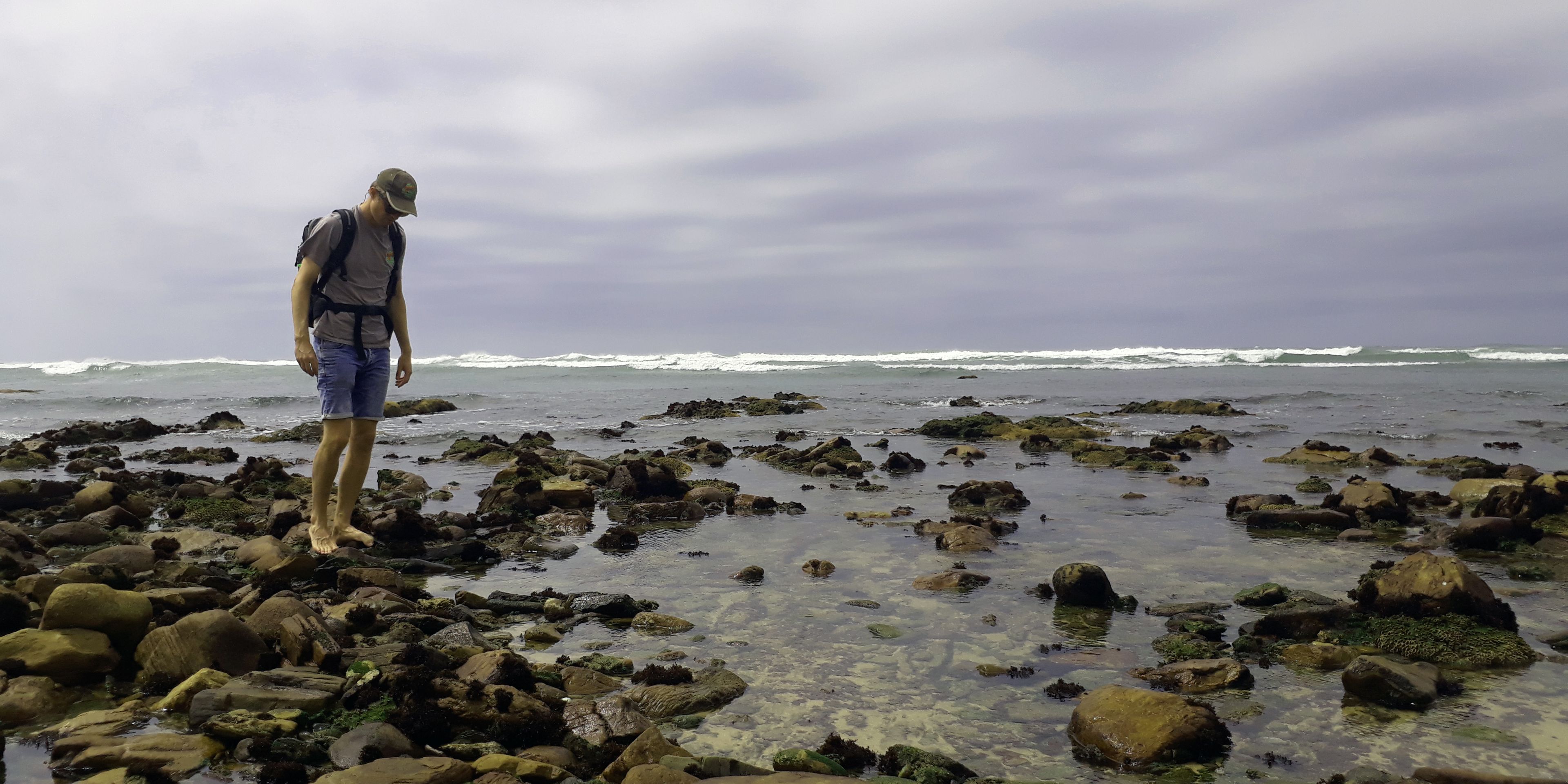 Aufnahme eines Marine Guide-Studenten, der ueber kleine Felsen an der Kueste Suedafrikas klettert