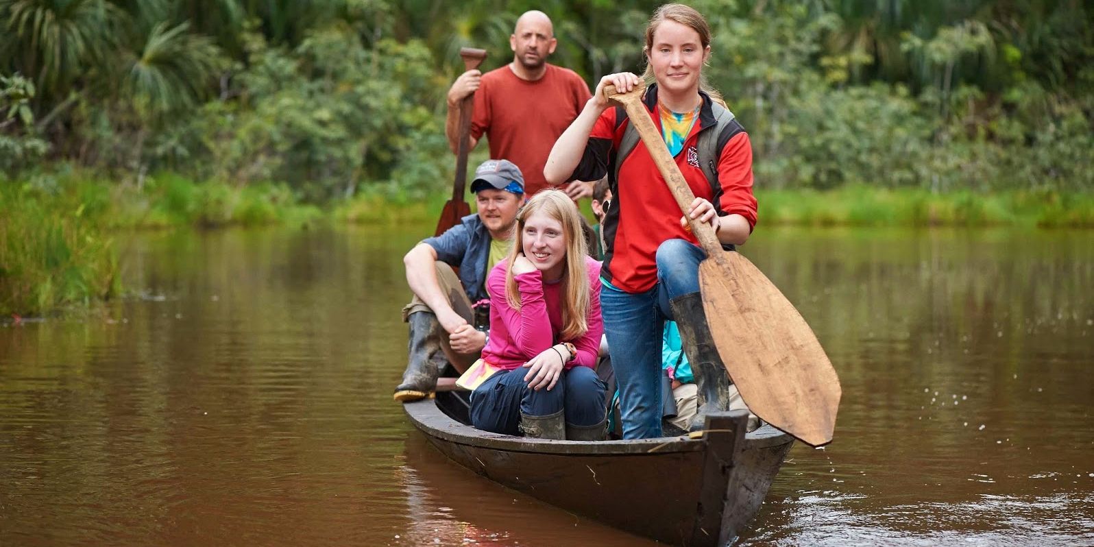 Eine Familie faehrt zusammen mit einem Ranger per Boot ueber einen Fluss im Amazonas