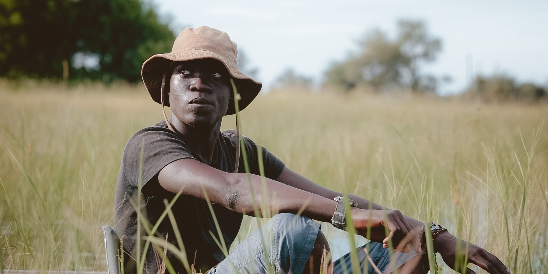 Ein Guide sitzt in einem Boot auf einem Gewaesser im afrikanischen Busch