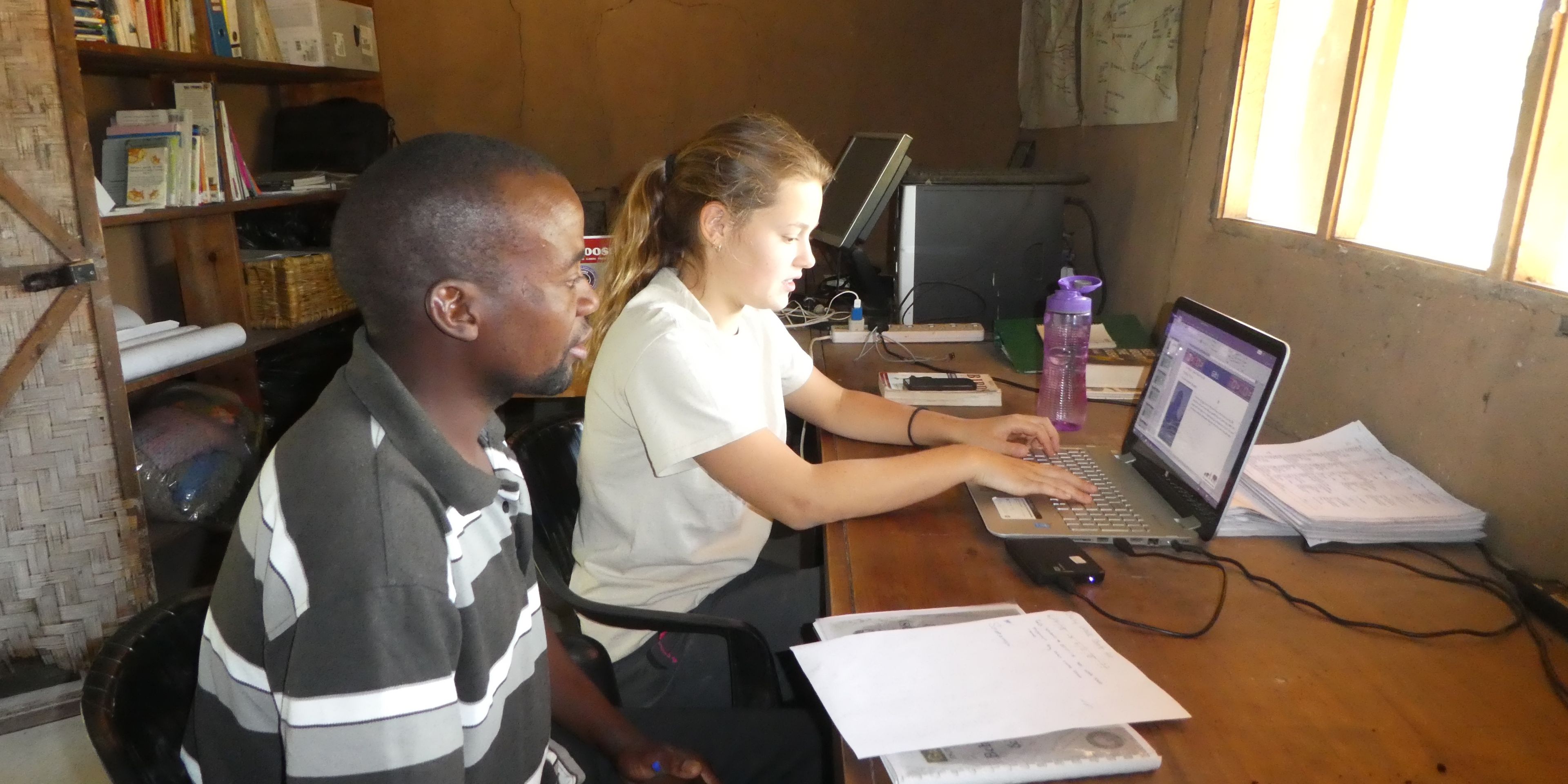 Eine Freiwillige und ein Teamleiter des Elefantenprojekts in Sambia sitzen zusammen im Camp-Buero und arbeiten