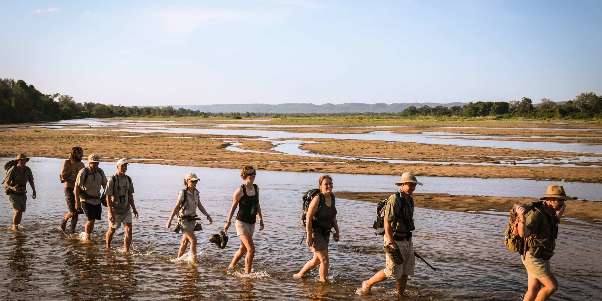 Der Rangerkurs watet auf einer Pirschwanderung durch eine Wasserstelle im afrikanischen Busch